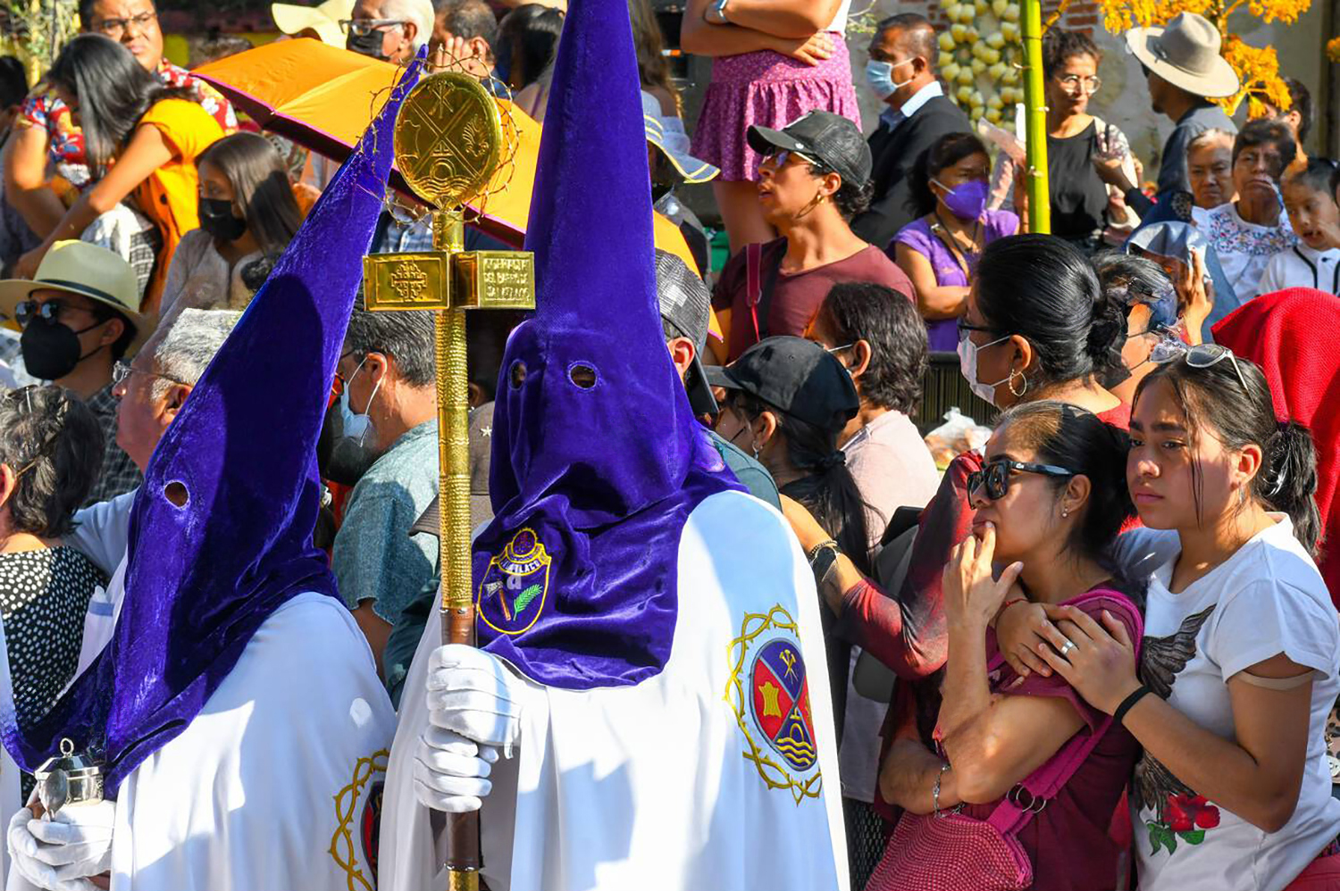 Hooded penitents in purple and white robes participating in the solemn Good Friday Procesión del Silencio in Oaxaca City, Mexico.