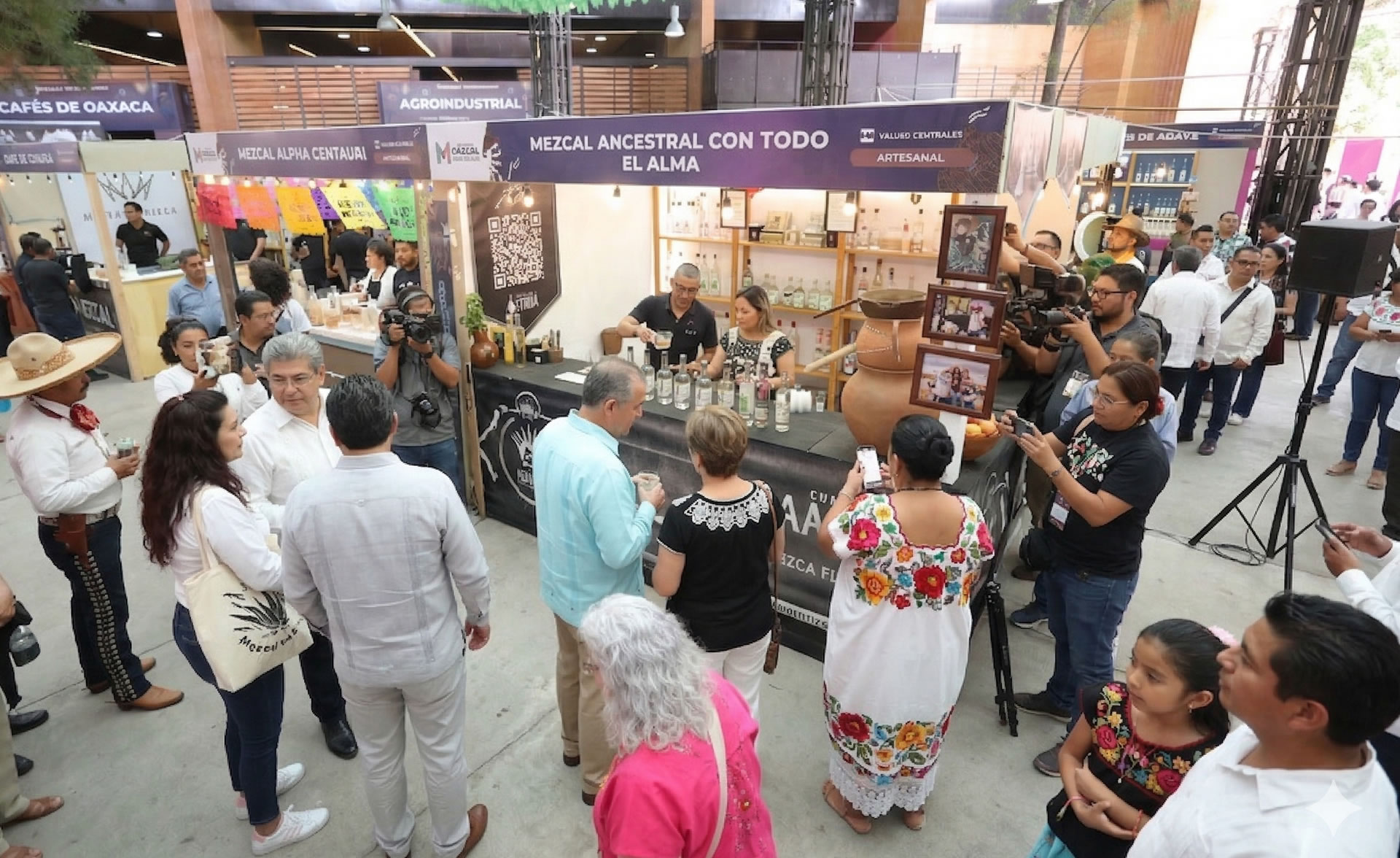 A lively Oaxaca festival scene with traditional food stalls, mezcal tastings, and visitors enjoying local culture in the city.